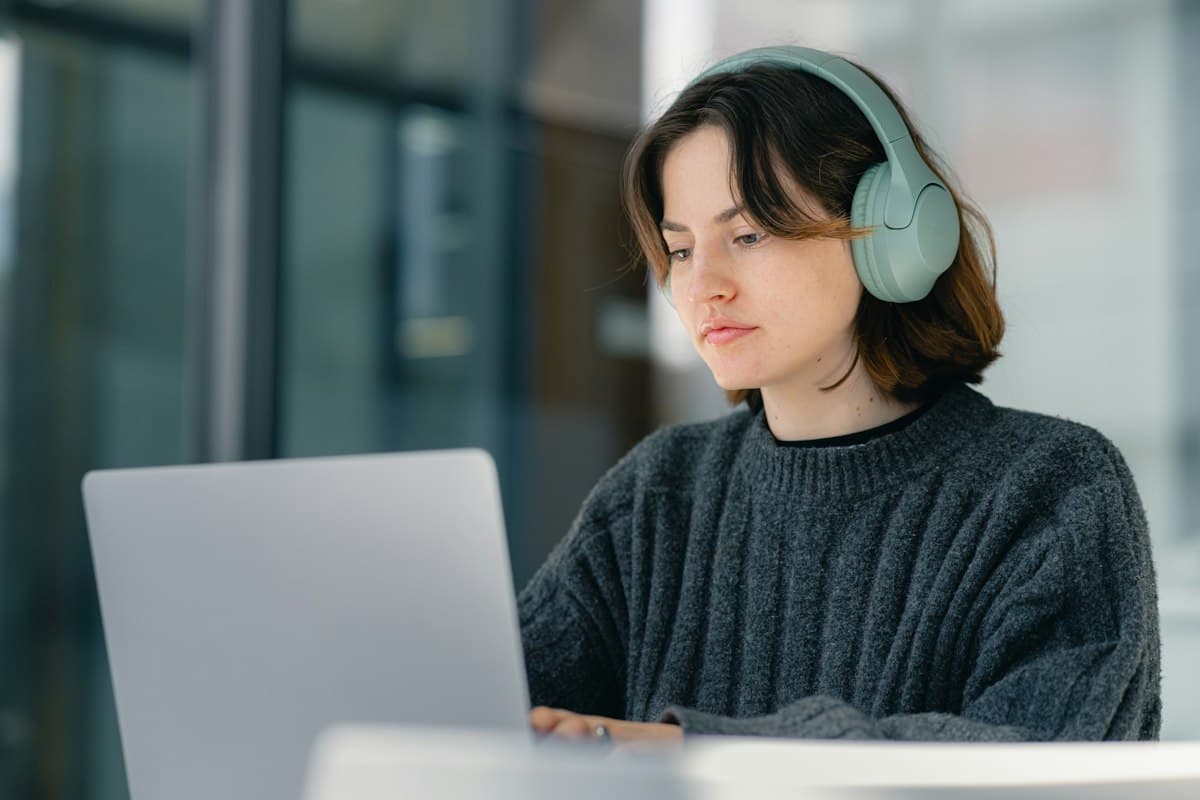 Una estudiante con auriculares estudia frente a su computadora