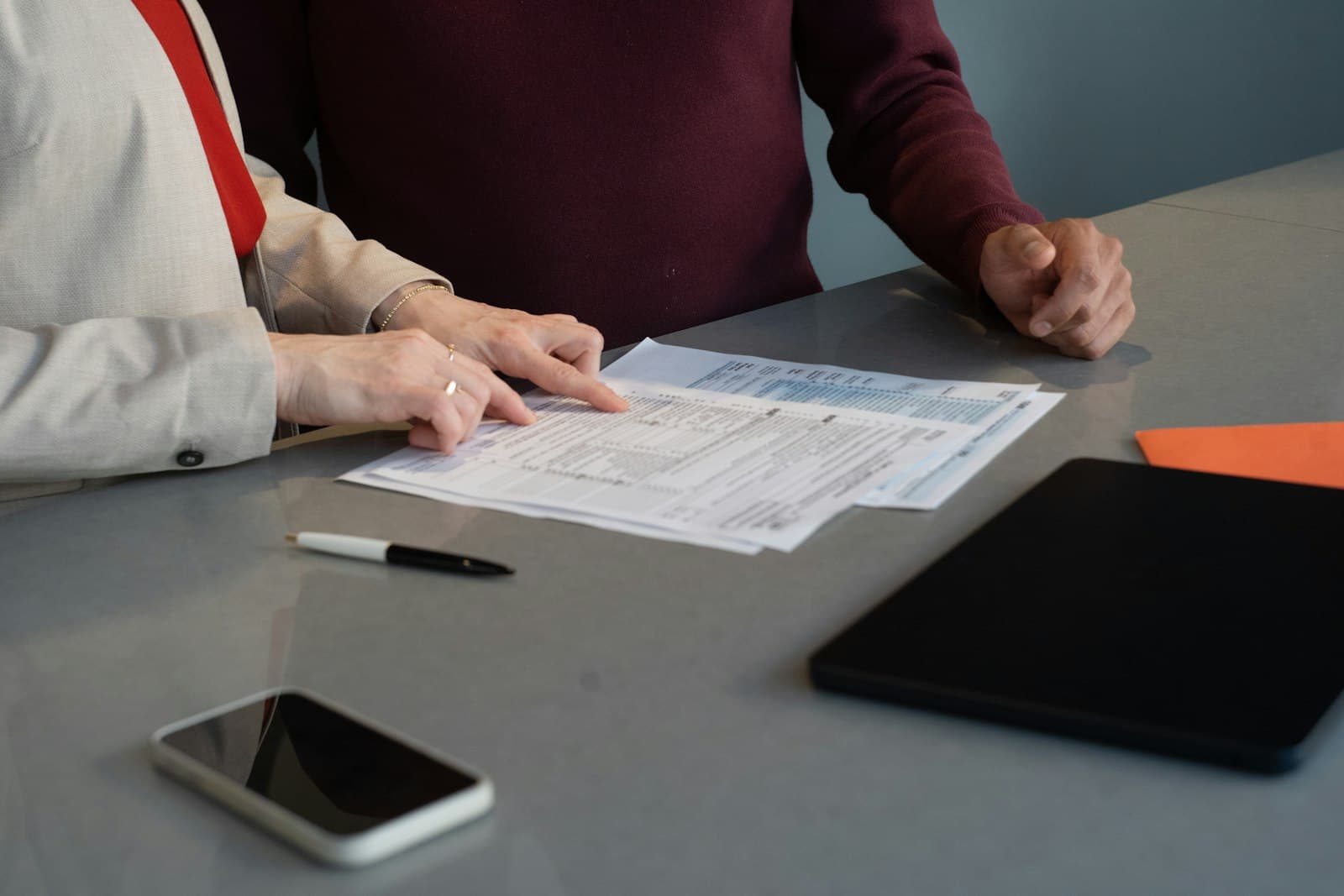 Two people review documents on an office table