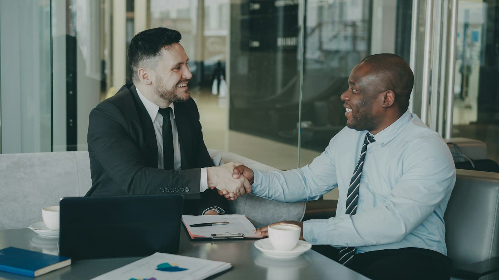 Two men in suits shake hands at a business meeting