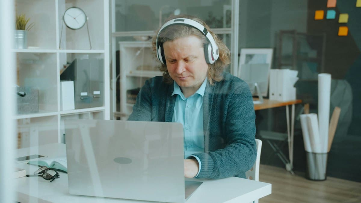 An employee with headphones takes a course on his laptop at the office